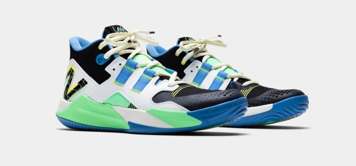 Side view of white, black, and green New Balance tennis shoes.